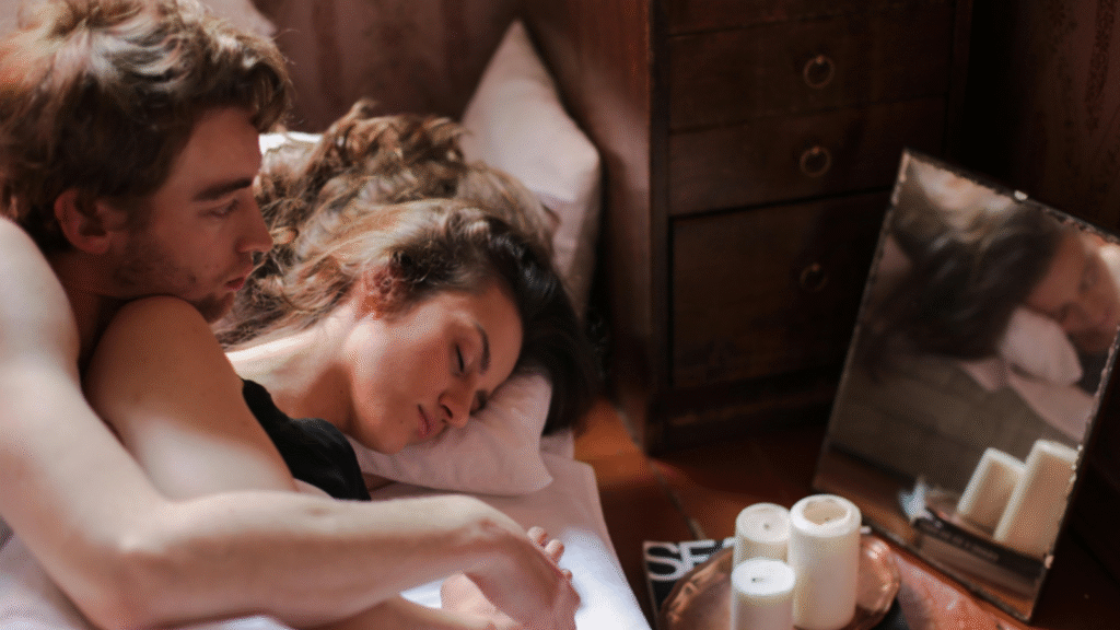 A couple sleeps peacefully together in a cozy bed, illuminated by soft candlelight